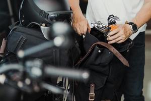 Der Fahrer bereitet die Werkzeuge vor und steckt sie vor einer Reise in die Sattel- oder Seitentasche. Motorradreisekonzept. selektiver Fokus foto