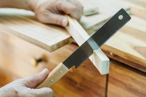 tischler mit japanischer säge oder zugsäge, querschneiden auf holz auf dem tisch, heimwerker und holzbearbeitungskonzept. selektiver Fokus foto