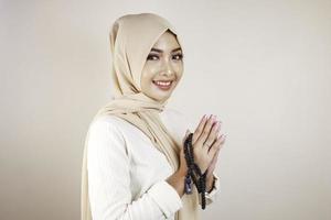 Porträt einer fröhlichen jungen schönen asiatischen muslimischen Frau, die lächelt und Gebetsperlen hält. Eid Mubarak-Konzept foto