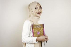 junge asiatische muslimische frau, die den koran lächelt und hält foto
