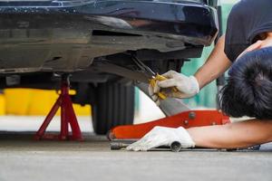 Automechaniker, der das Aufhängungssystem inspiziert, Konzept zur Überprüfung des Zustands des Autos vor der Fahrt foto