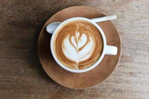 schöner morgenkaffee auf holztisch, heißer latte art kaffee foto