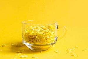 transparente Schüssel mit Mais- und Mehrkornflocken auf gelbem Hintergrund. schnelles und gesundes frühstück foto
