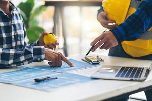 ingenieur und architekt treffen sich, arbeiten und zeigen auf zeichnungen im büro zur besprechung. ingenieurwerkzeuge und baukonzept, ingenieure und architekten brainstormen. foto