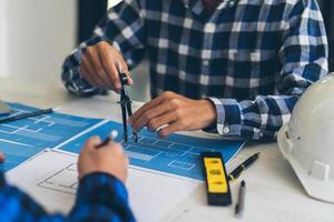 handzeichnungsplan des ingenieurs der person auf blaupause mit architektenausrüstung, architekten, die am tisch diskutieren, teamarbeit und arbeitsablaufkonstruktionskonzept. foto