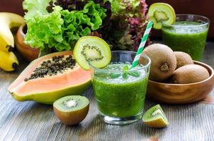 grüner tropischer Smoothie mit Kiwi, Papaya und Salatblättern foto
