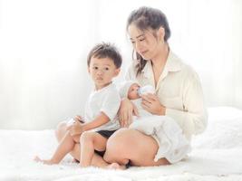 Eine schöne asiatische Frau hält ihr neugeborenes Baby mit Liebe und Wertschätzung und füttert sie mit Glück foto