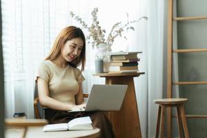 Porträt einer asiatischen jungen Frau, die im Café an Laptop und Finanzbericht arbeitet. foto