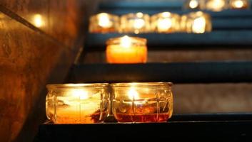 Kerze und Beleuchtung auf dem Regal nachts in der Kirche, beten Sie für Frieden foto