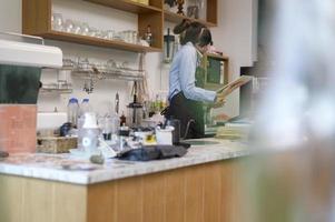 junge serviceorientierte Barista-Frau, die im Café arbeitet foto