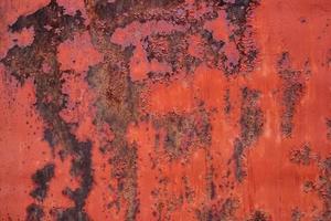 Alte rot lackierte Metalloberfläche mit ausgedehnten Korrosionsflecken im Hintergrund. foto
