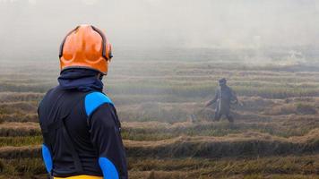 Feuerwehrleute mit Stroh verbrennenden Bauern. foto