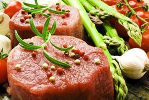 rohes Steak mit grünem Spargel auf Holzbrett