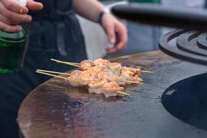 Garnelen kochen, Garnelenspieße auf dem Grill beim Street Food Festival - Nahaufnahme foto