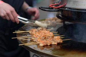 Garnelen kochen, Garnelenspieße auf dem Grill beim Street Food Festival - Nahaufnahme foto