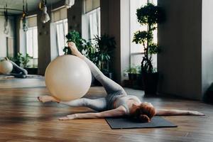 frau, die bauchmuskelübungen mit fitball auf yogamatte macht foto