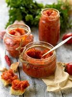 leckere Dosen Chili und Tomaten Adjika auf Holz Hintergrund foto