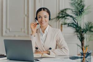 Geschäftsfrau, die ein Headset trägt und den Arbeitstag im modernen Büro genießt foto