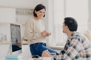 familienpaar bespricht künftige investitionen, posiert im coworking space, arbeitet am modernen computer, schaut sich in der kaffeepause glücklich an, will einkaufen, arbeitet remote zu hause foto