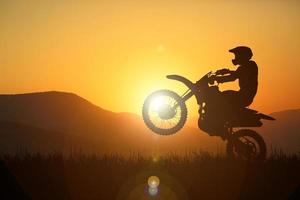 Silhouette eines Motocross-Motorrads, das das Vorderrad anhebt. Abenteuer- und Aktionskonzepte foto