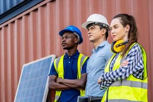 Selbstbewusstes Porträt von Vorarbeitern und Ingenieuren in Uniformen, die vor den Containern und der Solarzelle stehen, nachhaltiges Entwicklungskonzept foto