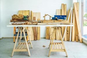 Hintergrundbild von Tischlerarbeitsplatz, Tischlerarbeitstisch mit verschiedenen Werkzeugen und Holzschneideständer mit Holzspänen foto