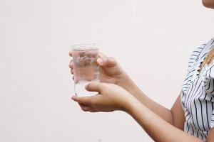 asiatische frau, die ein glas kaltes wasser zum trinken hält foto