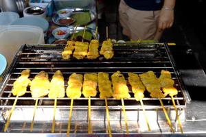 Schweinefleisch-Satay-Sticks grillen auf rostfreiem Röster zum Verkauf, Thailand. foto