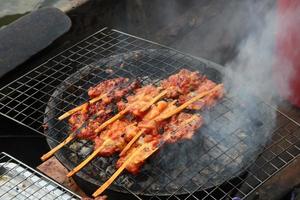 hähnchen auf rost grillen auf einheimischem herd, straßenessen in thailand. foto