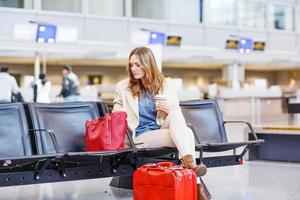 Frau am internationalen Flughafen wartet auf Flug am Terminal foto