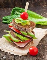 Sandwich mit Schinken und frischem Gemüse auf Holzhintergrund foto