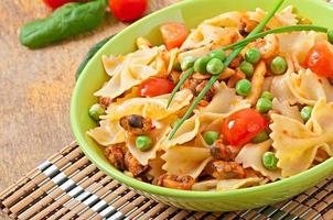 Farfalle-Nudeln mit Meeresfrüchten, Kirschtomaten und grünen Erbsen foto