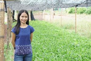 asiatische Frau mit weißem Hemd glücklich im Gemüsegarten foto