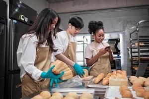 Drei junge Freunde und Startup-Partner von Brotteig und Gebäck, die mit hausgemachten Backjobs beschäftigt sind, während sie Online-Bestellungen kochen, verpacken und an Bäckereien liefern, Kleinunternehmer foto