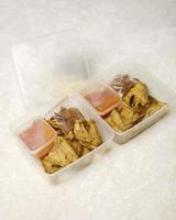 Hähnchen umwickelt mit indonesischen Gewürzen. Hühnchenstücke sind fertig zum Braten. verzehrfertige lebensmittel in kartonverpackungen komplett mit chilisauce etc. lebensmittelverpackungsmodellbox für vorlage. Fokusunschärfe. foto