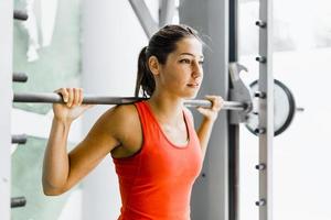 junge schöne Frau, die Gewichte in einem Fitnessstudio hebt foto