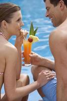 Paar, das tropisches Getränk am Pool teilt