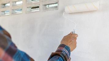 Hand eines Malers, der einen Plan hält, um die weiße Wand zu streichen foto