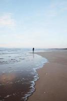 Person, die am Strand spazieren geht foto