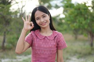 asiatische frau, die glücklich lächelt, hebt ihre hand zum himmel naturhintergrund foto