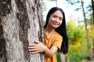 asiatische frauen, die bäume umarmen, das konzept der liebe für die welt foto