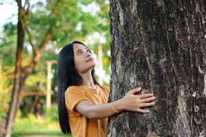 asiatische frauen, die bäume umarmen, das konzept der liebe für die welt foto