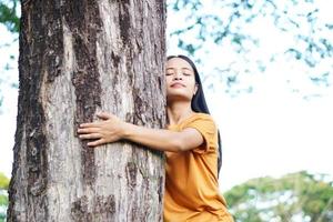 asiatische frauen, die bäume umarmen, das konzept der liebe für die welt foto