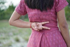 Frau, die zwei Finger hinter ihrem Rücken hält foto