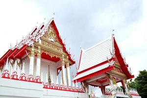 Vorderseite der roten und weißen Colr-Kirche im thailändischen alten Stil von Watkhunyingsomjean und bewölktem Himmelshintergrund, Thailand foto