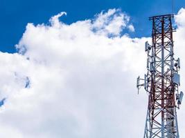 Telekommunikationsgeräte auf dem Stahlkonstruktionsturm und den weißen Wolken am blauen Himmel foto