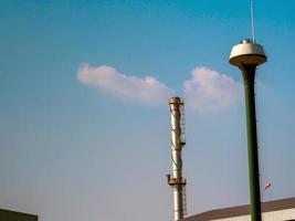 Fabrikschornstein und der Wasserturmtank am blauen Himmel foto