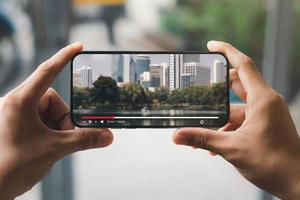 Online-Film-Streaming mit Smartphone. junger mann, der einen film auf einem handy mit einem imaginären videoplayer-dienst anschaut.