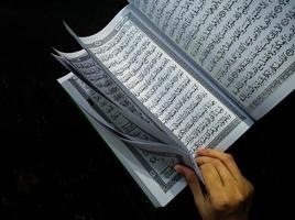 mann, der koran hält und liest. islamischer Hintergrund foto