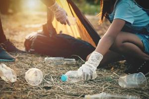 frauenhand, die müllplastikflasche zur reinigung im park aufhebt foto